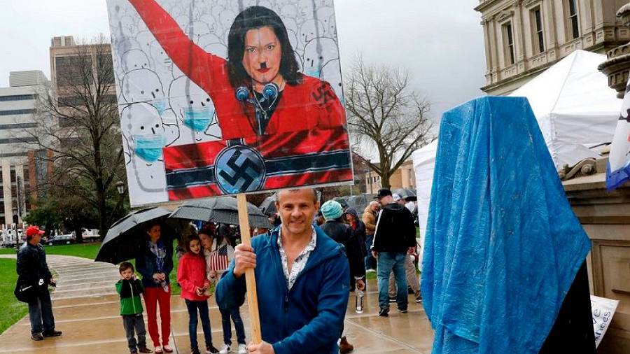live free protester holds Gretchen Whitmer poster depicted as Adolph Hitler